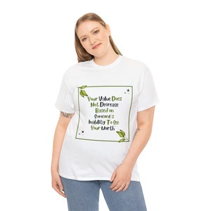 Puede incluir: Camiseta blanca con un borde de hojas verdes alrededor de una cita que dice "Tu valor no disminuye en función de la incapacidad de alguien para ver tu valor."