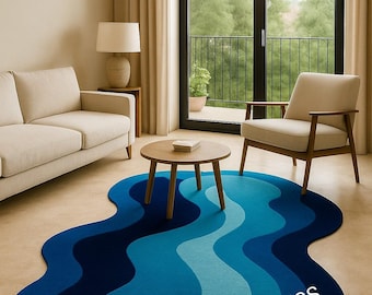 May include: An irregular, organic-shaped area rug featuring a layered, wavy pattern in shades of navy, royal, and light blue. The rug displays the text ANSARI ART RUGS in white lettering across the surface, set against a neutral-toned floor.