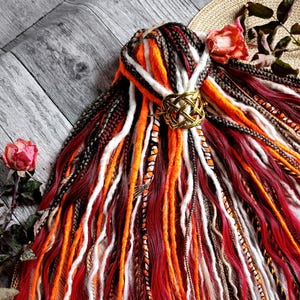 Puede incluir: Un letrero de madera hecho a mano con la palabra "Bienvenido" en una fuente juguetona. El letrero está pintado de blanco con un acabado envejecido y presenta un diseño floral en tonos rosas y verdes. Mide aproximadamente 30 cm de ancho.