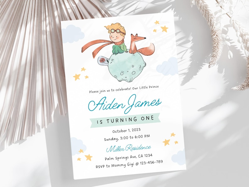May include: A blue and white invitation card with a cartoon illustration of a little prince on a planet with a fox. The text on the card reads "Please join us to celebrate! Our Little Prince Aiden James is turning one. October 1, 2023. Sunday, 3:00 to 6:00 PM. Miller Residence. Palm Springs Ave, CA 1234. RSVP to Mommy Gigi @ 123-456-789."