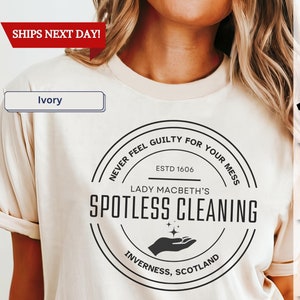 May include: Ivory t-shirt with a black and white circular graphic that says "Never feel guilty for your mess. Est. 1606 Lady Macbeth's Spotless Cleaning. Inverness, Scotland."