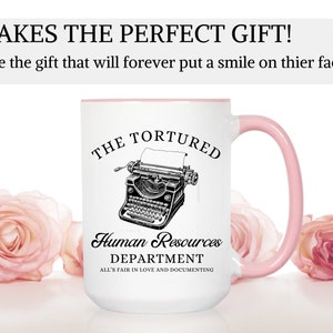 K&ouml;nnte beinhalten: Eine wei&szlig;e Keramik-Kaffeetasse mit rosafarbenem Rand und Henkel. Die Tasse zeigt eine Schwarzwei&szlig;illustration einer alten Schreibmaschine mit dem Text "The Tortured Human Resources Department All's Fair in Love and Documenting".