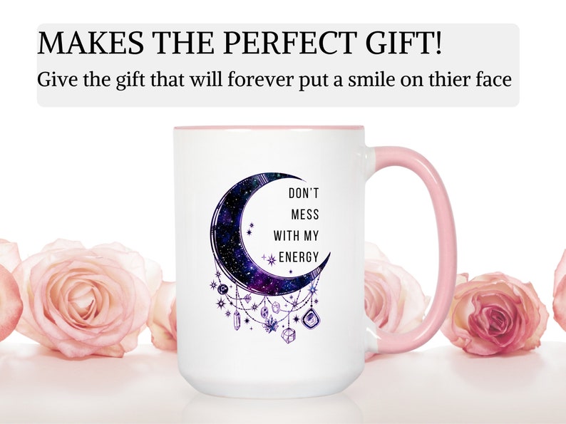 May include: White ceramic mug with a pink rim and handle. The mug features a crescent moon with a galaxy design and the text "Don't mess with my energy".