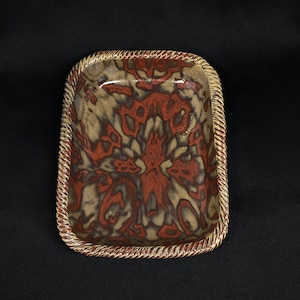 May include: A square ceramic serving dish with a brown and red marbled glaze. The dish has a rope-like design around the edge.