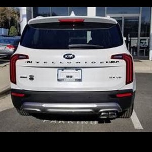 May include: White Kia Telluride SUV with black trim and rear bumper. The rear window has a black sticker that says "I can" and another sticker that says "A Harley".
