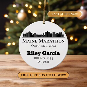 May include: White ceramic ornament with a black silhouette of the Portland, Maine skyline. The text "Maine Marathon" is printed in black, along with the date "October 6, 2024", the runner's name "Riley Garcia", bib number "1234", and finish time "03:39:11".