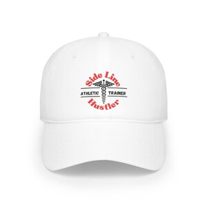 Könnte beinhalten: Weiße Baseballkappe mit einem schwarzen und roten gestickten Logo, auf dem "Side Line Athletic Trainer Hustler" steht.