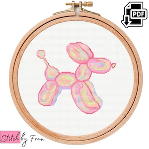 Op de afbeelding: Een kruissteekpatroon van een roze ballondier in de vorm van een hond. Het ballondier bevindt zich in een houten borduurring.