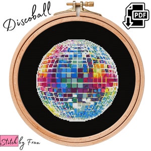 Può includere: Uno schema di punto croce di una palla da discoteca colorata in un cerchio da ricamo in legno. Lo schema presenta un arcobaleno di colori su uno sfondo bianco.
