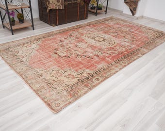 May include: A vintage rug with a faded pink and cream color scheme. The rug has a floral pattern and a border with a geometric design.