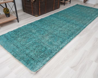 May include: A teal blue runner rug with a faded floral pattern. The rug has a distressed look and is made of a soft, woven material.