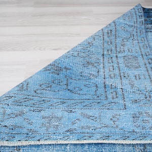 May include: A blue and black patterned rug with a fringed edge. The rug is folded in half and the pattern is visible on both sides.