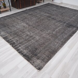 May include: A dark gray area rug with a distressed, vintage look. The rug has a subtle pattern and a slightly faded appearance.