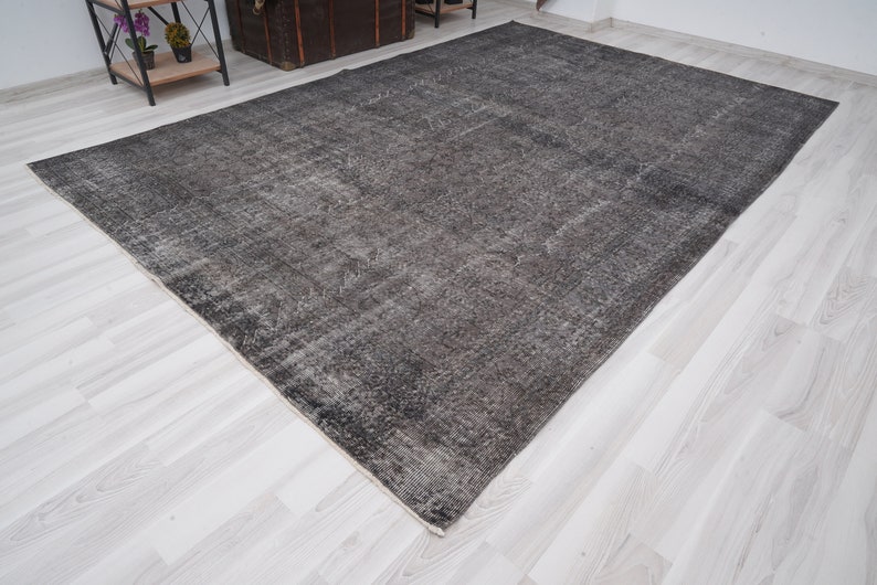 May include: A dark gray area rug with a distressed, vintage look. The rug has a subtle pattern and a slightly faded appearance.