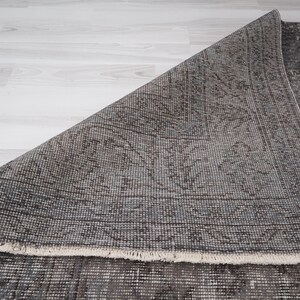May include: A close-up of a gray and brown patterned rug with a fringed edge. The rug is folded in half, revealing the underside.
