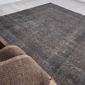 May include: A dark gray rug with a subtle pattern. The rug is made of a soft, woven material and has a distressed look.