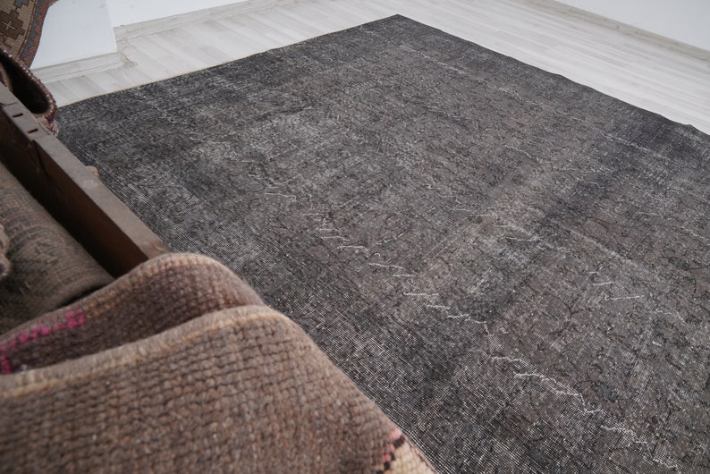 May include: A dark gray rug with a subtle pattern. The rug is made of a soft, woven material and has a distressed look.