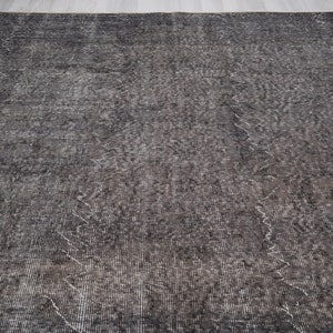 May include: A dark gray rug with a subtle pattern. The rug has a distressed look and a slightly textured surface.