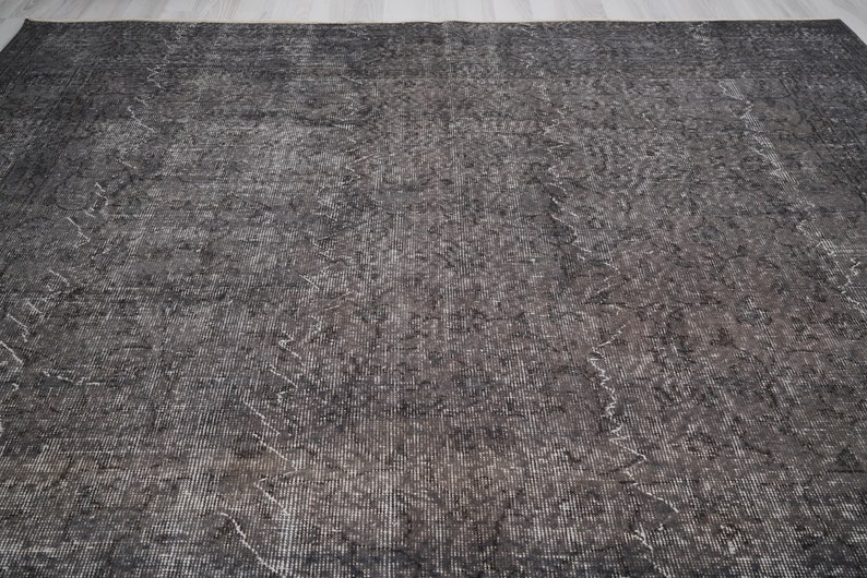 May include: A dark gray rug with a subtle pattern. The rug has a distressed look and a slightly textured surface.
