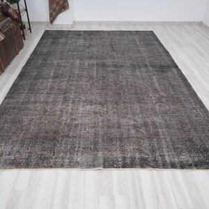 May include: A dark gray vintage rug with a distressed look. The rug has a subtle pattern and a faded appearance.
