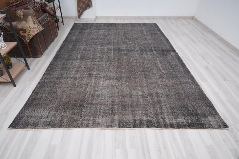 May include: A dark gray vintage rug with a distressed look. The rug has a subtle pattern and a faded appearance.