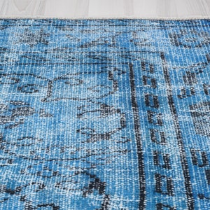 May include: A blue and white vintage rug with a faded, distressed look. The rug has a geometric pattern with black accents.
