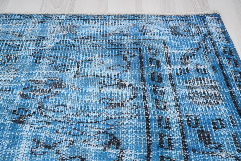 May include: A blue and white vintage rug with a faded, distressed look. The rug has a geometric pattern with black accents.