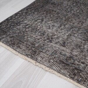 May include: A close-up of a gray and white patterned rug with a fringe border. The rug is made of a soft, woven material.