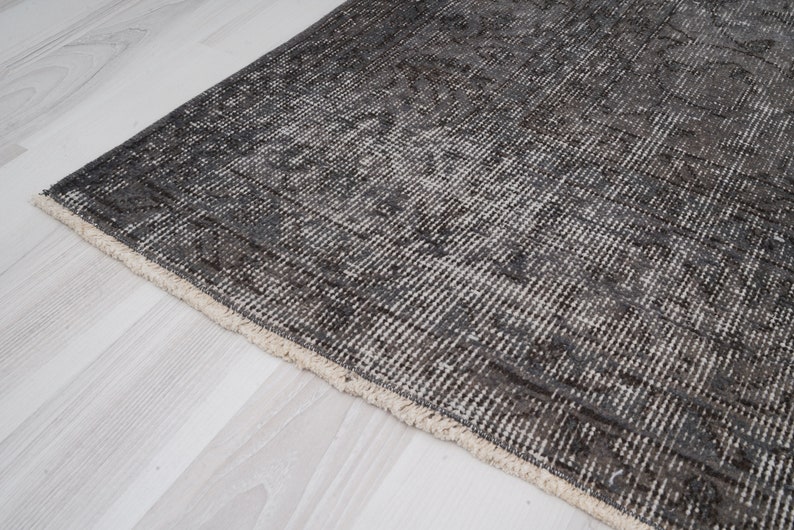 May include: A close-up of a gray and white patterned rug with a fringe border. The rug is made of a soft, woven material.
