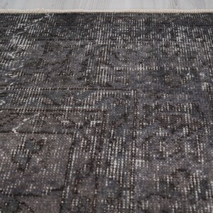 May include: A dark gray rug with a subtle pattern of white and gray. The rug has a distressed look and a slightly textured surface.