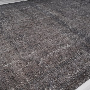 May include: A dark gray area rug with a distressed, vintage look. The rug has a subtle pattern throughout.
