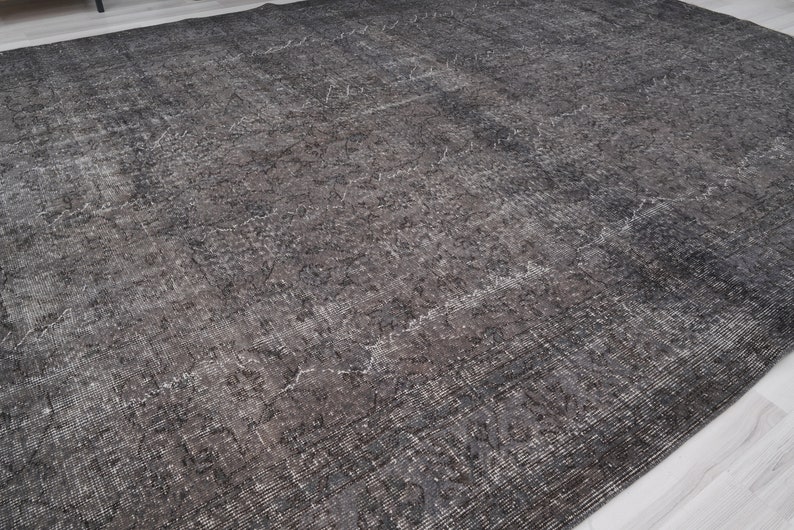 May include: A dark gray area rug with a distressed, vintage look. The rug has a subtle pattern throughout.