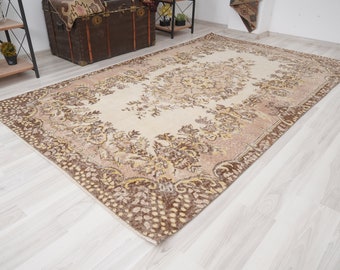 Op de afbeelding: Een vintage vloerkleed met een bloemmotief, een crèmekleurige achtergrond en bruine en beige accenten. Het vloerkleed heeft een verweerde uitstraling en is gemaakt van een zacht, geweven materiaal.