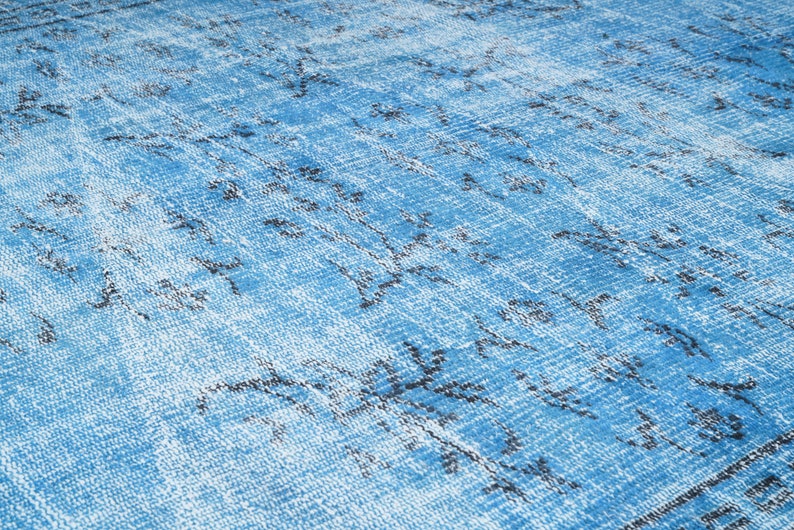 May include: A blue and white patterned rug with a distressed look. The rug has a faded blue background with a white pattern of lines and swirls.