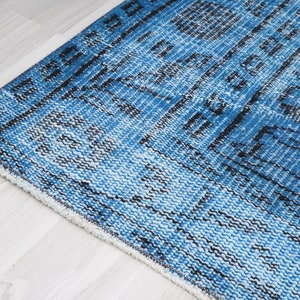 May include: Close-up of a blue and white patterned rug with a fringe border. The rug has a distressed, vintage look.
