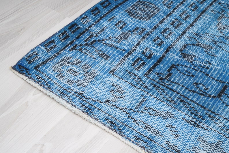 May include: Close-up of a blue and white patterned rug with a fringe border. The rug has a distressed, vintage look.