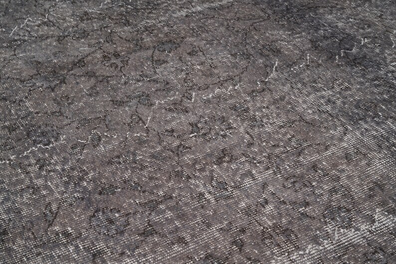 May include: A close-up of a gray and white patterned rug with a distressed, vintage look.