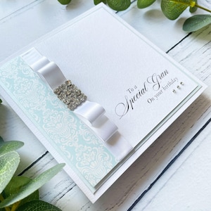 Besondere Gran Geburtstagskarte. Handgemachtes Geschenk. Handgefertigte Karte. Luxus Design, mit Band & Diamanté Verzierung. Baby blau und weiß.