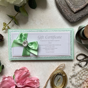 Handgefertigter Geschenkgutschein, Geschenkkarte, Ticket, Gutschein. Personalisiert mit den Ereignisdetails. Präsentiert in einer Geschenkbox. Mintgrün und weiß.