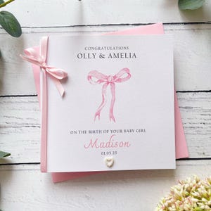 Nouvelle carte pour bébé fille, joli nœud, noms des parents, nom du bébé et date de naissance personnalisés. Un nœud et une fleur sont finis à la main
