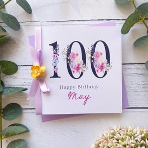 100e anniversaire | Personnalisé | Grands chiffres avec des fleurs | Ruban et noeud | Lavande et jaune | Prénom féminin | Joyeux anniversaire