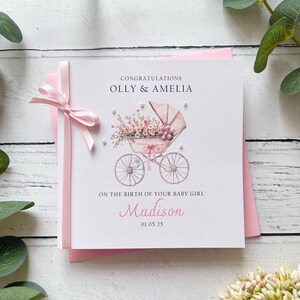 Nouvelle carte de bébé fille, joli design vintage de landau, prénoms personnalisés des parents, nom du bébé et date de naissance. Un noeud et des fleurs à la main