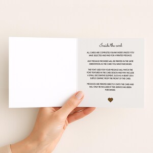 May include: An open, white greeting card held by a person's hand, revealing the inside. Text on the right side reads "Inside the card" followed by details about printed messages and design elements. A small gold heart graphic is at the bottom.