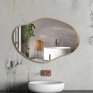 May include: A gold-framed, irregular-shaped mirror with a white bathtub and a potted plant reflected in the glass.