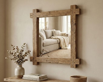May include: A rectangular mirror with a rustic, wooden frame. The frame is constructed from thick, weathered wood beams, with visible knots and grain. The mirror reflects a living room scene with a beige sofa and a rug. The overall aesthetic is natural and cozy.