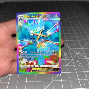 May include: A holographic Mega Metagross EX trading card with 230 HP. The card features a blue, metallic creature with a gold cross on its face, surrounded by a vibrant, rainbow-colored background. Text includes Gatling Slug, 100+ damage, and Mega Evolution EX rule.