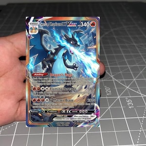May include: A collectible trading card featuring Mega Charizard X VMAX with 340 HP. The card displays a black dragon-like creature breathing blue flames against a city background, with text detailing the Dragon's Rage ability and attacks.
