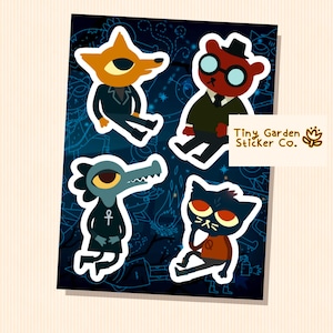 May include: A sheet of four cartoon character stickers. The stickers feature a fox, a bear, a crocodile, and a cat, each with unique designs and expressions. The background is dark blue with a starry pattern. The text "Tiny Garden Sticker Co." is visible.