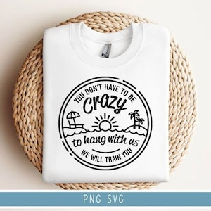 May include: White t-shirt with a black and white graphic design. The graphic features a beach scene with a sun, palm trees, and the text "You don't have to be crazy to hang with us. We will train you."