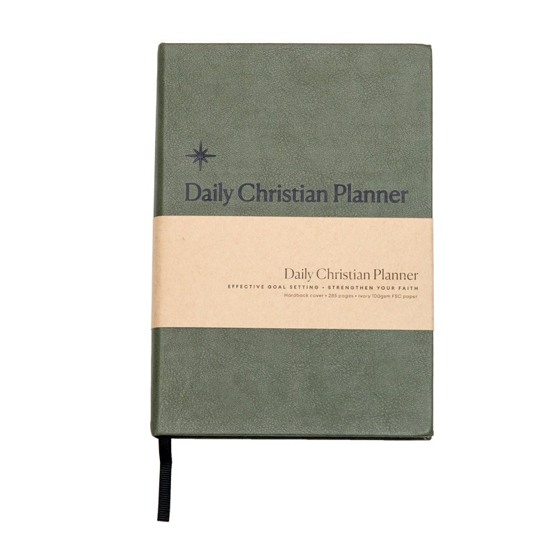 May include: A green hardcover daily Christian planner with a brown paper band that reads "Daily Christian Planner, Effective Goal Setting - Strengthen Your Faith, Hardback cover - 200 pages - heavy 100gsm FSC paper".